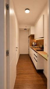 a kitchen with white cabinets and a wooden floor at Tirone Luxury Rooms in Cirò Marina