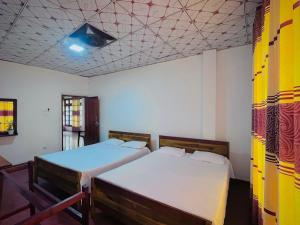 a room with two beds and a ceiling with at River Park Holiday Home in Badulla