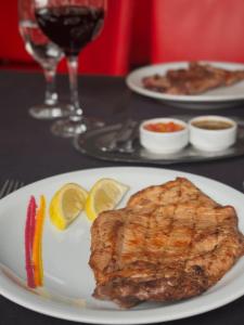 a white plate with a piece of fish and lemon slices at Marchetti Hotel Comedor in Miramar