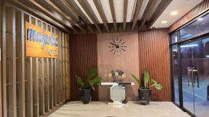 a lobby with a clock on the wall and plants at HOTEL MAJESTIC in Palembang