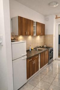 a kitchen with wooden cabinets and a white refrigerator at Apartment Gonzales in Mostar