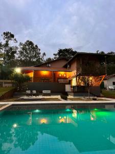 a house with a swimming pool in front of it at Pousada Jamacaii in Araxá