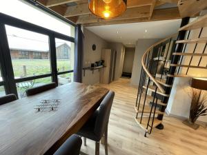 a dining room with a table and a spiral staircase at duplex confort Le pre marty in Albepierre-Bredons