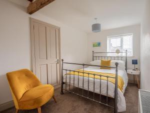 a bedroom with a bed and a yellow chair at Y Cwtsh in Llandeilo