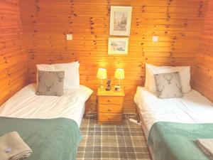 two twin beds in a room with wooden walls at Braemar Lodge Cabins in Braemar