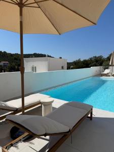 a swimming pool with two lounge chairs and an umbrella at Villa Artemis III in Žman