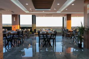 a dining room with tables and chairs and large windows at Midyat Bay Grand Hotel in Midyat