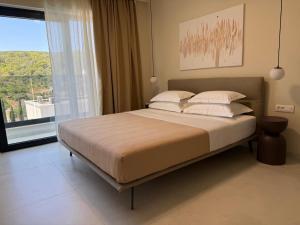 a bed in a bedroom with a large window at Villa Artemis III in Žman +9 photos