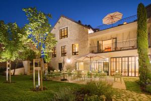 a building with tables and chairs in a yard at Chez Gratien Hôtel Bistro Spa in Villeneuve-dʼAveyron