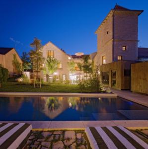 a house with a swimming pool in front of a building at Chez Gratien Hôtel Bistro Spa in Villeneuve-dʼAveyron
