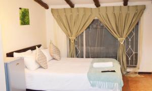 a bedroom with a white bed with a window at Harmony Guest House in Johannesburg +62 photos