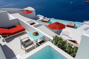 a pool with chairs and umbrellas and a table at Alti Santorini Luxury Suites in Megalochori