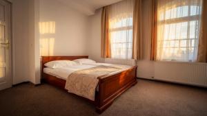 a bedroom with a wooden bed with two windows at Pearl Home in Békéscsaba