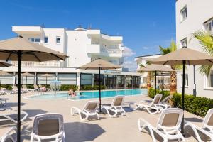 a group of chairs and umbrellas next to a pool at Sirena Garden Resort in Tale
