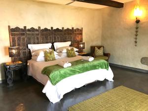 a bedroom with a large bed with a green blanket at Tinkers Lakeside Lodge - Kruger in White River