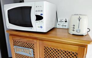 a microwave sitting on top of a wooden table at Shallow Pig Cottage in Parys