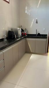 a kitchen with white cabinets and a black counter top at Chácara Encanto do Horizonte in Ibiapina