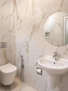 a white bathroom with a toilet and a sink at Hotel Aleksandrus Jardin in Durrës +9 photos