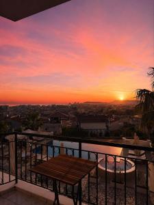 a sunset from a balcony with a wooden bench at Hotel Aleksandrus Jardin in Durrës