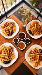 a wooden table with plates of waffles and other food at Hotel Aleksandrus Jardin in Durrës