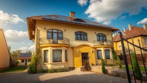 a yellow house with a balcony on top of it at Pearl Home in Békéscsaba