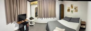 a bedroom with a bed and a flat screen tv at Kundalini Buzios in Búzios