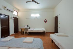 a room with two beds and a table in it at Omji Ashram - Maa Anandmayi in Vrindāvan