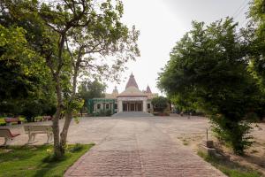 a large building in a park with a brick road at Omji Ashram - Maa Anandmayi in Vrindāvan
