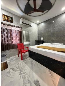 a bedroom with a red chair and a bed at Aditya Residency in Mādhavaram