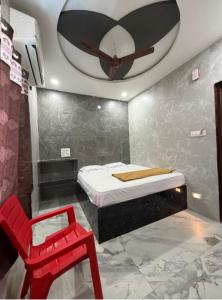 a bedroom with a bed and a red chair at Aditya Residency in Mādhavaram