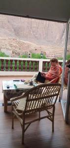 a man sitting on a balcony looking out of a window at La maison blanche in Tinerhir +8 photos