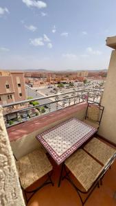 a table and chairs on a balcony with a view of a city at Hotel Almou in Ouarzazate
