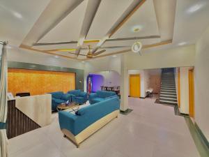 a living room with blue couches and a staircase at Hotel Royal Sunset in Karachi
