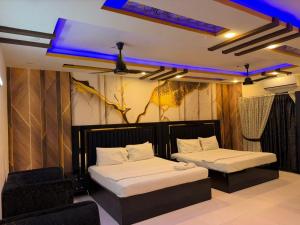 a bedroom with two beds and a chair in it at Hotel Royal Sunset in Karachi