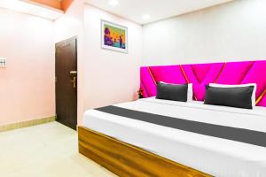 a bedroom with a large bed with a pink headboard at Hotel O Barsana in Pātipukur +22 photos