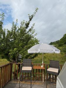 two chairs and an umbrella on a deck at Skyla Glamping in Ambrolauri