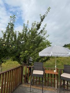 a deck with two chairs and an umbrella at Skyla Glamping in Ambrolauri