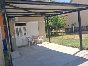 a pergola with two chairs in front of a house at Sunshine- self sheck in in Čačak