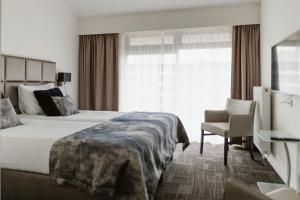 a hotel room with a bed and a chair and a window at Hotel Torpedoloods in Hoek van Holland