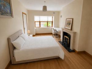 a bedroom with a white bed and a fireplace at 28 Rathevan View Rosdarragh Portlaoise in Portlaoise
