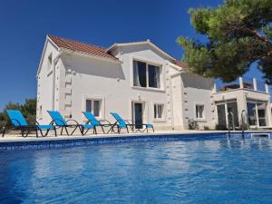 a villa with a swimming pool and blue chairs at Vila Nikola in Pučišća