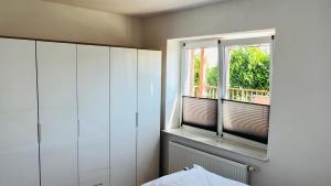 a bedroom with white cabinets and a window at Admiralshütte XXL - für 12 Personen zwischen Dornumersiel und Bensersiel in Dornum