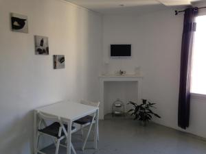a white living room with a table and a television at La Maisonnette in Courthézon