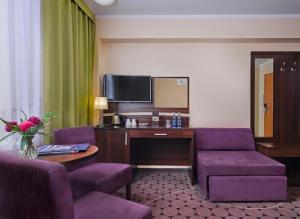 a hotel room with purple chairs and a desk with a tv at Lumen in Krakow