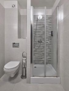 a bathroom with a toilet and a glass shower at Lumen in Krakow +3 photos