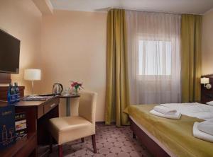 a hotel room with a bed and a desk and a window at Lumen in Krakow