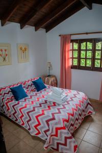 a bedroom with a bed with a red and white comforter at Cabañas Costa Alta in Mina Clavero +46 photos