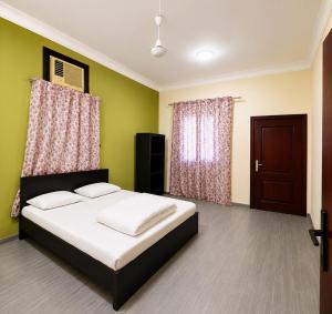 a bedroom with a bed with green walls and a door at Liva Residency in Salalah +4 photos