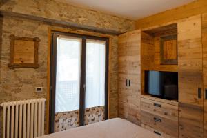 a bedroom with wooden walls and a tv and a window at BERTUZZI HOMES "Luxury Chalet" in Aprica