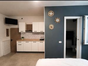 a kitchen with white cabinets and a blue wall at Mercury Room in Limbiate
